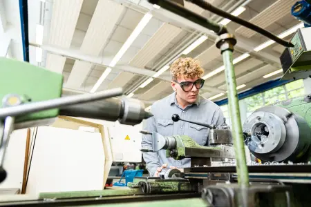 Studierender mit Schutzbrille arbeitet an einer Maschine