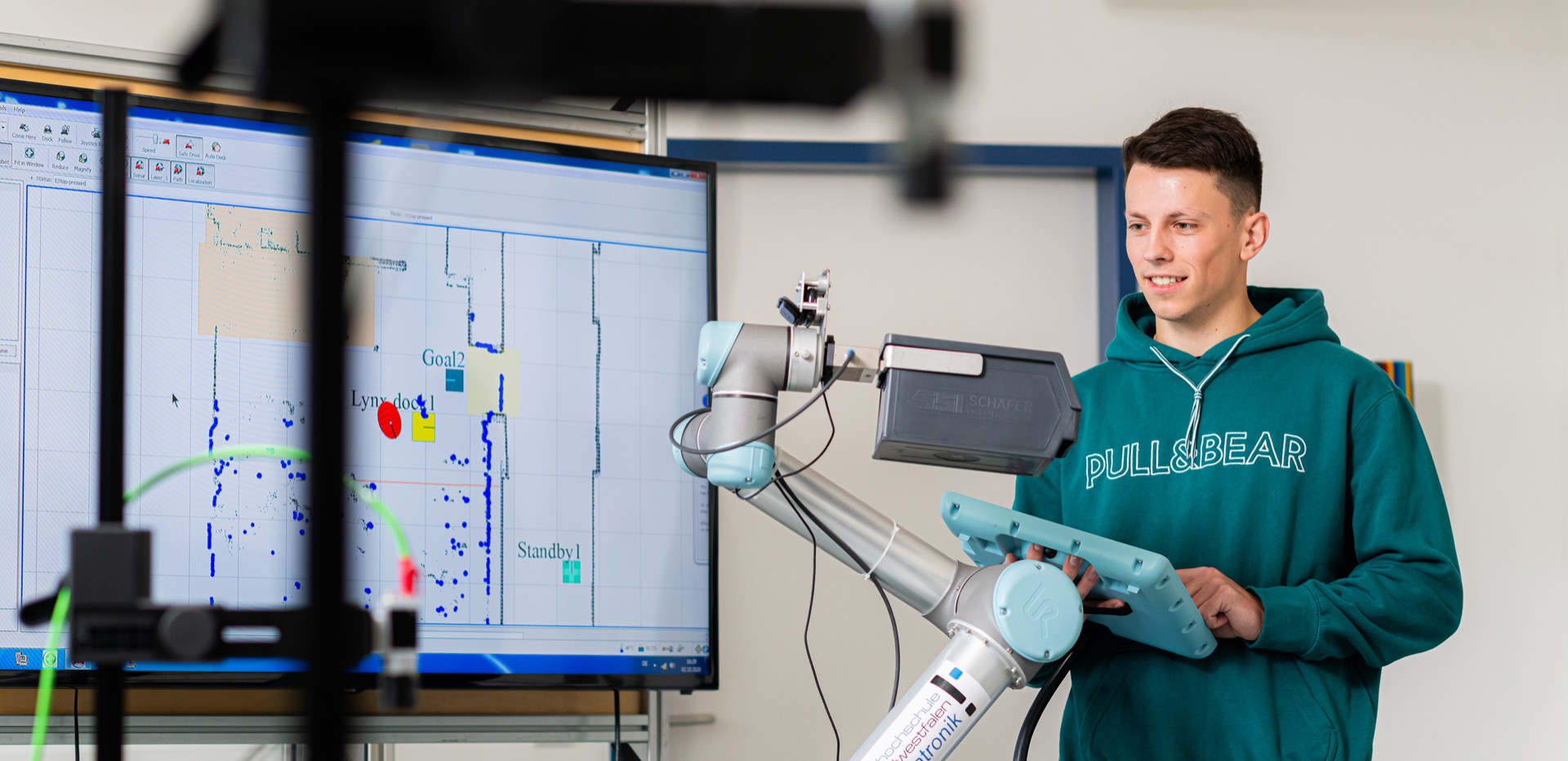 Studierender steuert einen Roboterarm