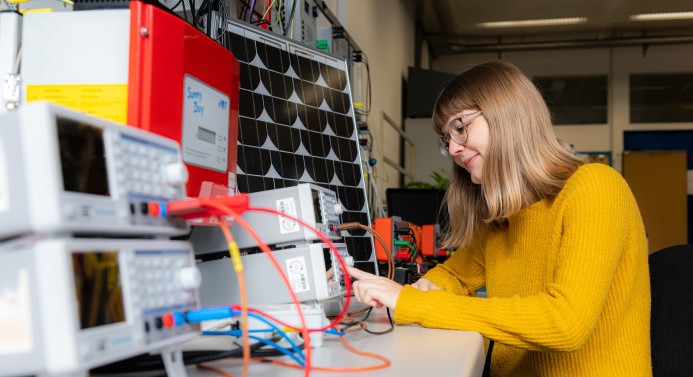 Eine Studentin sitzt vor elektronischen Geräten.