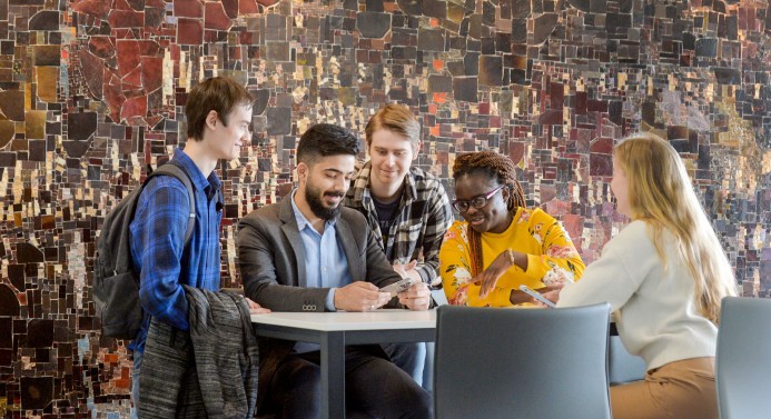 Studierende schauen gemeinsam in ein Smartphone.