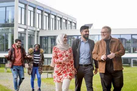 Studierende laufen in Grüppchen über den Innenhof am Hagener Standort und unterhalten sich.