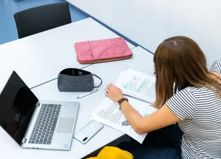 Studierende lernt mit Laptop und Unterlagen