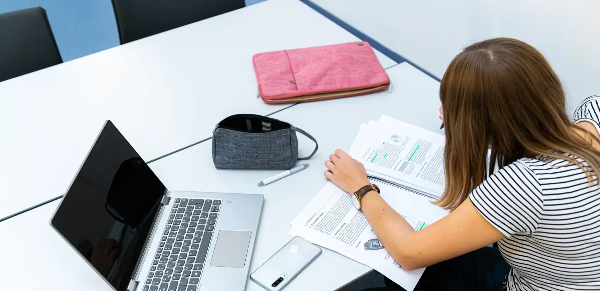 Studierende lernt mit Laptop und Unterlagen