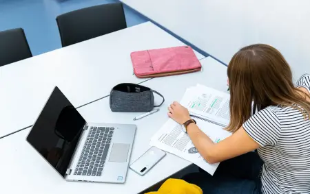 Studierende lernt mit Laptop und Unterlagen