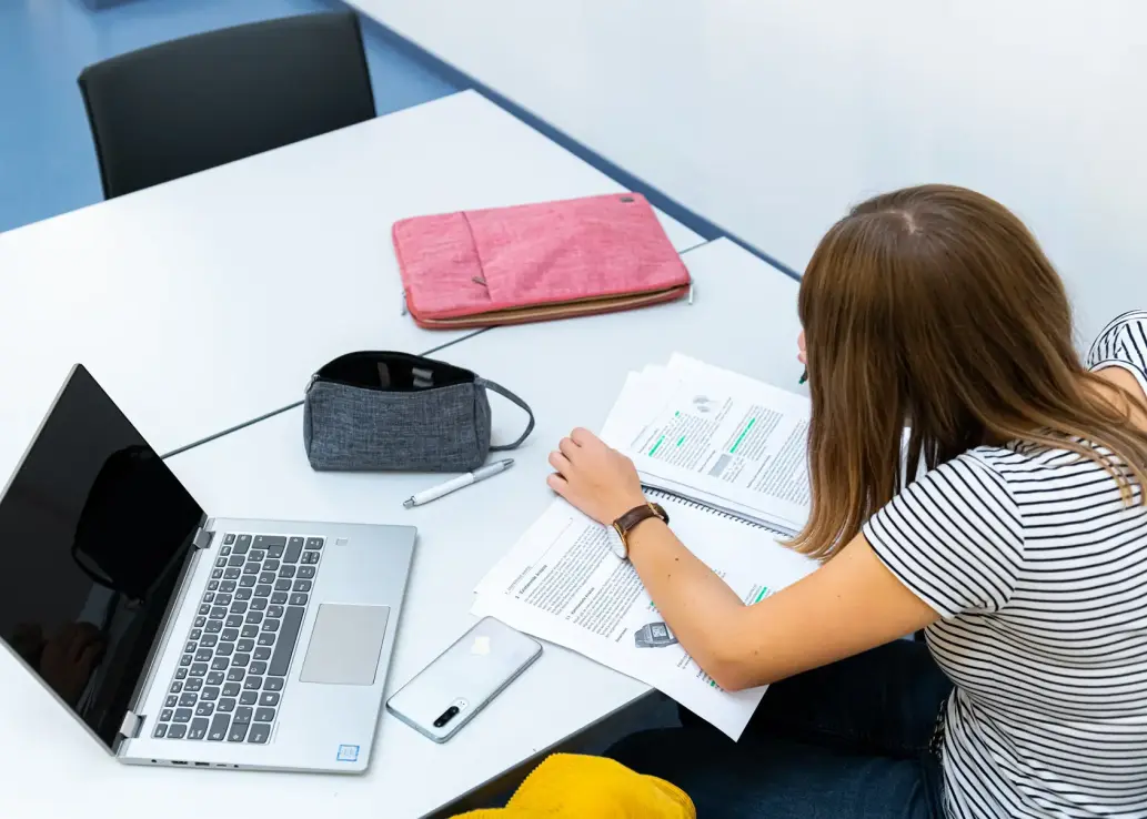 Studierende lernt mit Laptop und Unterlagen