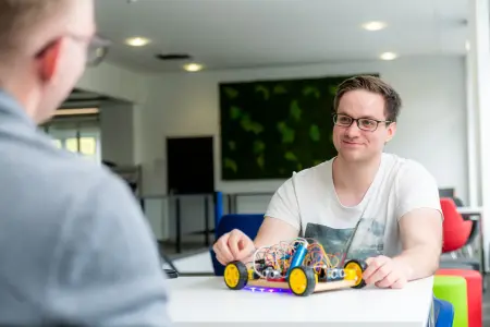 Studierender vor einem elektronischen Modell eines kleinen Autos