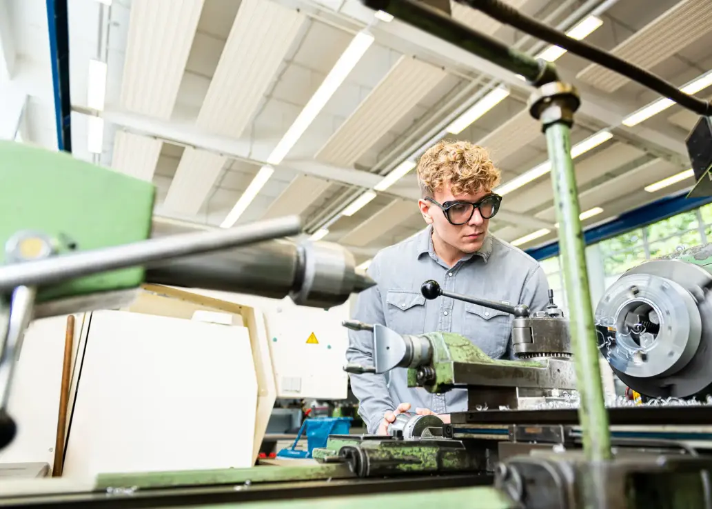 Studierender mit Schutzbrille arbeitet an einer Maschine