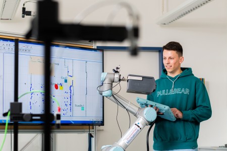 Studierender steuert einen Roboterarm