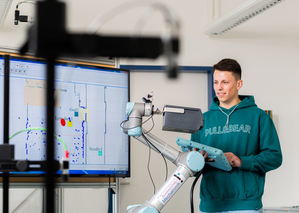 Studierender steuert einen Roboterarm