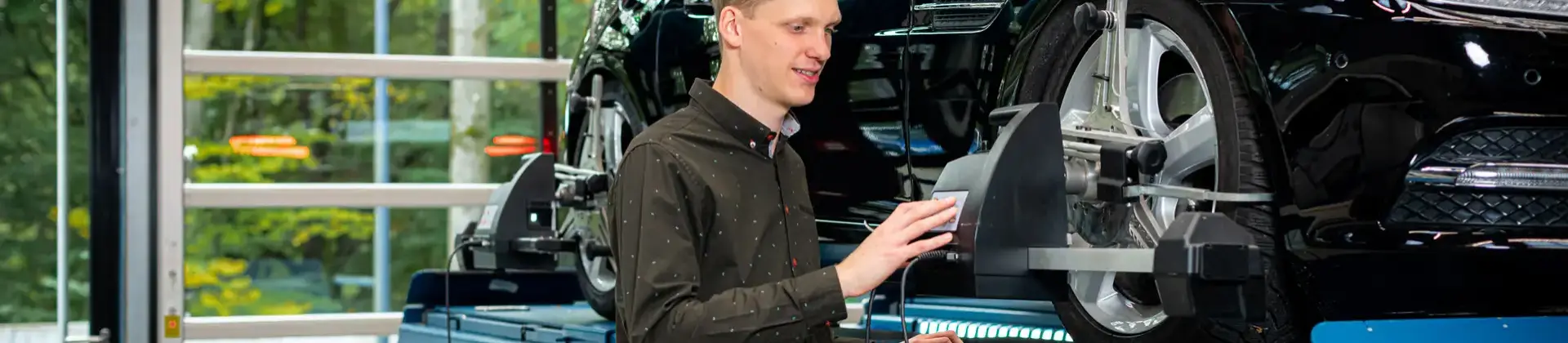 Student in der Werkstatt mit einem Auto auf der Hebebühne.