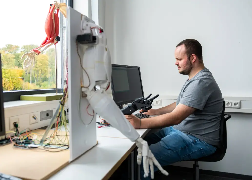 Studierender arbeitet mit Roboterarm