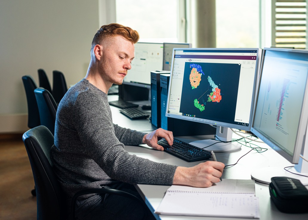Student vor mehreren Monitoren