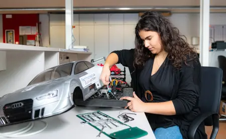 Studentin bastelt an einem Modell Auto.