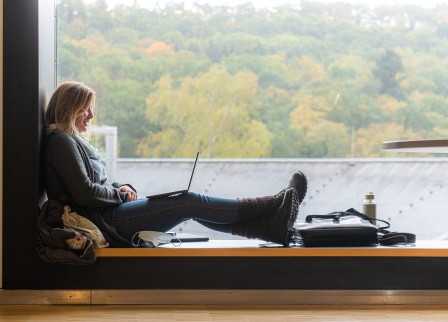 Studentin sitzt am Fenster mit einem Laptop