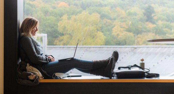 Studentin sitzt am Fenster mit einem Laptop