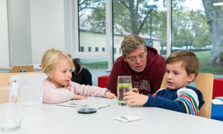 Kinder und eine Erwachsene sitzen am Tisch