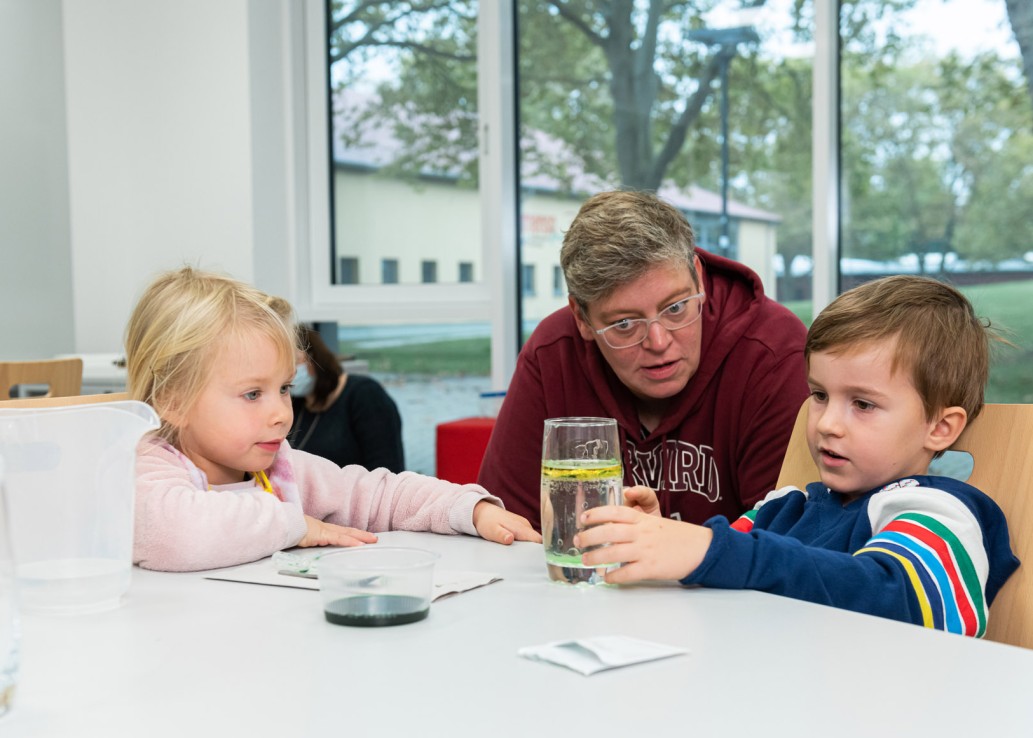 Kinder und eine Erwachsene sitzen am Tisch