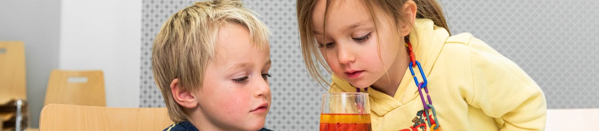 Zwei Kinder schauen sich ein volles Glas an