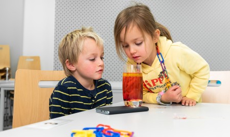 Zwei Kinder schauen sich ein volles Glas an