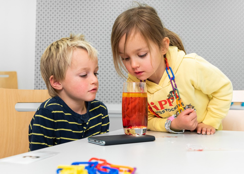 Zwei Kinder schauen sich ein volles Glas an