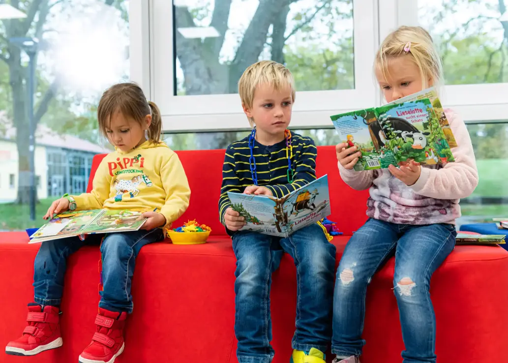 Drei Kinder schauen sich Bücher an