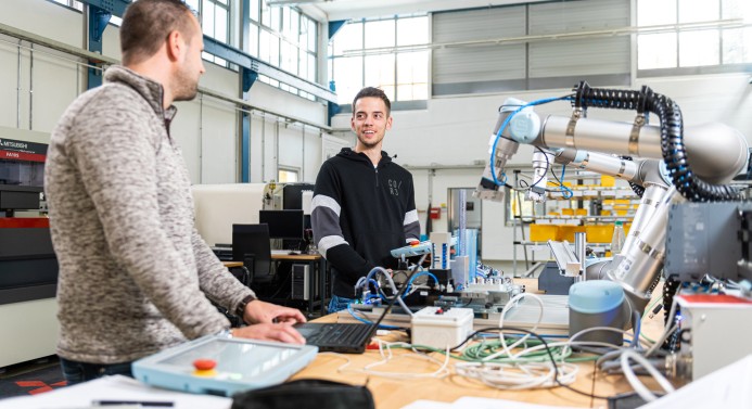 Zwei Studierende arbeiten an einem Universal Roboter