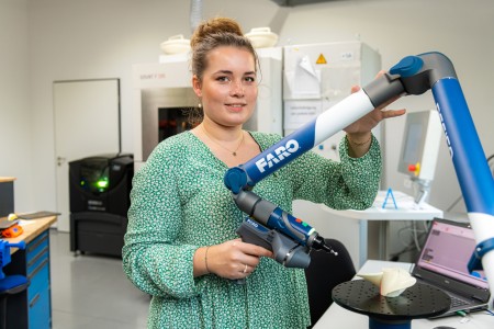 Junge Frau bedient eine Maschine und lächelt in die Kamera