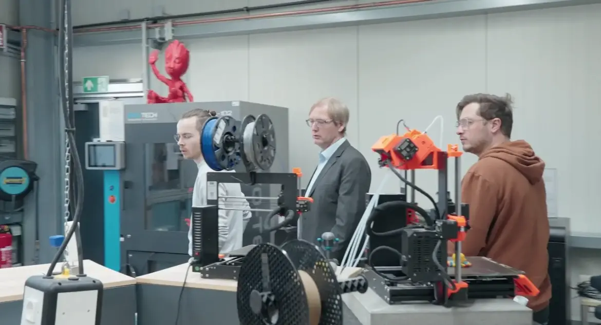 Drei Männer stehen vor Maschinen im Labor der Generativen Fertigung