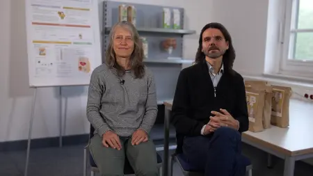 Dr. Iris Schröter und Prof. Dr. Marcus Mergenthaler sitzen in einem Raum, neben Ihnen ein Tisch auf dem unterschiedliche Porridge-Packungen stehen.