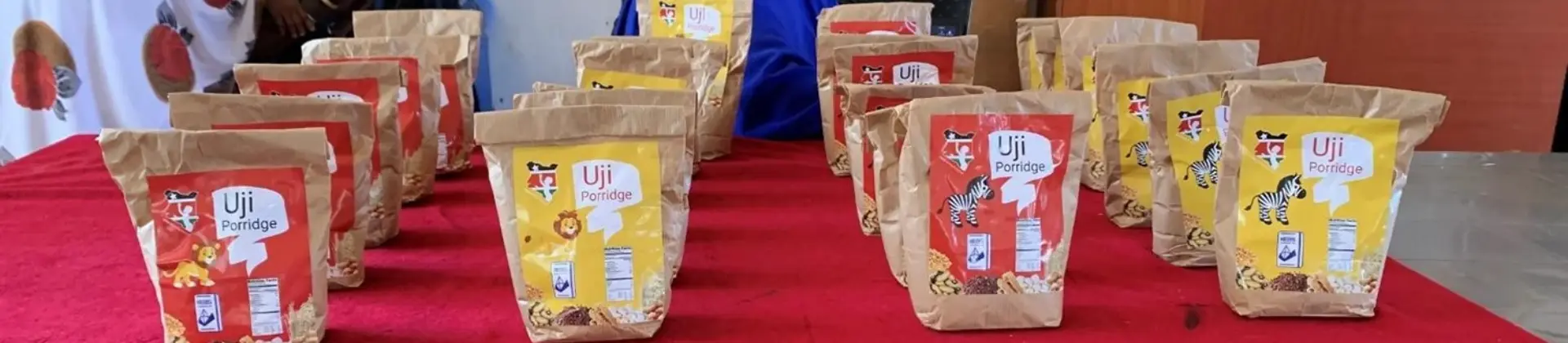 Auf einem Tisch stehen mehrere Porridge-Verpackungen mit unterschiedlich designten Labels in gelb oder rot, mit einem Zebra oder Löwen darauf.