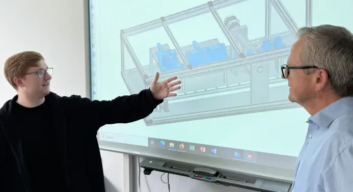Simon Wiechowski demonstriert Prof. Dr. Wolfgang Schütte das Modell seiner Montageanlage, die in wenigen Wochen aufgebaut werden kann. 