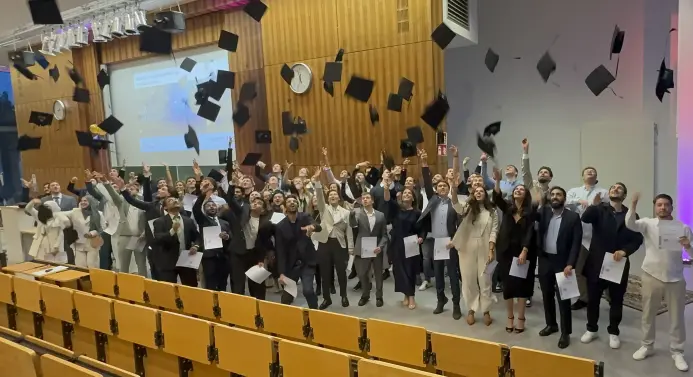 Studierende werfen im Hörsaal ihre Hüte in die Luft.