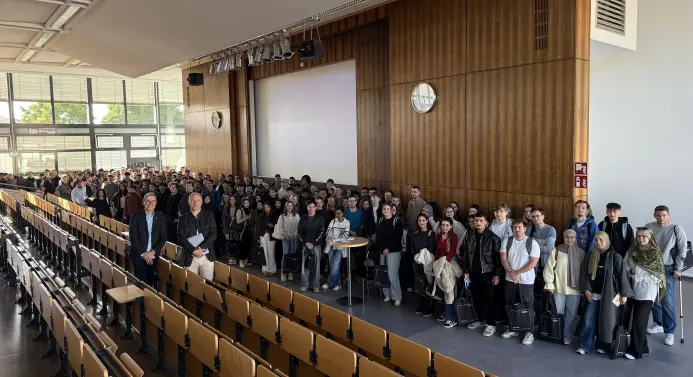 Eine große Gruppe von Studierenden mit zwei Professoren im Audimax.