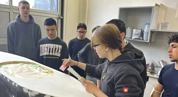 Die Auszubildende Celine im Lackier- und Karosseriezentrum Bremer bereitet mit den Jugendlichen eine Seifenkiste zur Lackierung vor