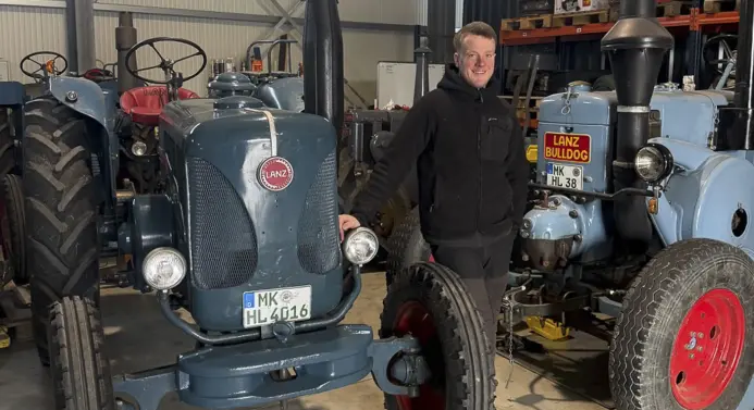 Max Willeke steht zwischen zwei Oldtimer-Traktoren.