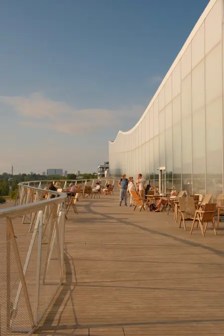 Blick auf eine umzäunte Terrasse, die an die Glasfront eines Gebäudes angrenzt.