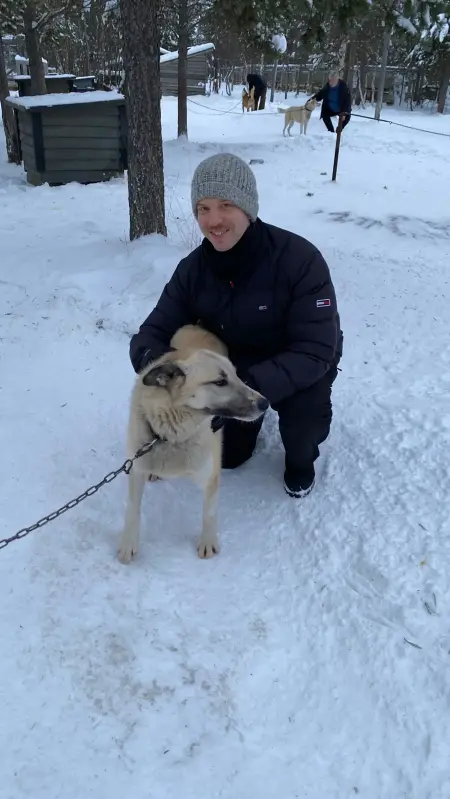 Ein Mann, Kai Zenker, im Schnee gemeinsam mit einem Schlittenhund.