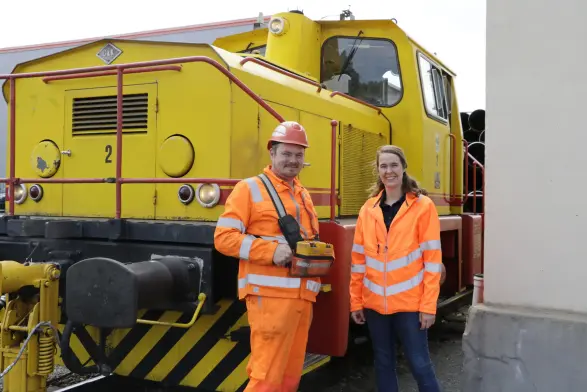 Ein Mann und eine Frau stehen vor dem Führerhaus der Hafenbahn. 
