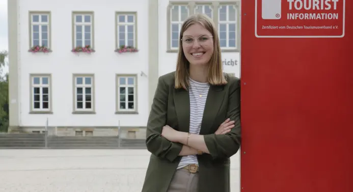 Eine Frau steht angelehnt an ein großes rotes Schild. Auf dem Schild steht 
