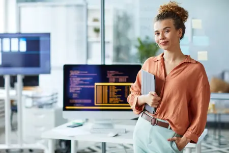 Berufstätige steht mit Tablet in der Hand in einem Unternehmen.