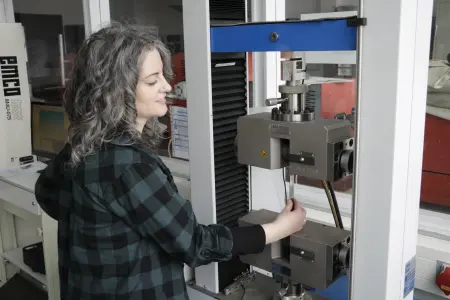 Melanie Frieling an der Zugprüfmaschine mit einer eingespannten Probe. Foto: Christian Klett, FH Südwestfalen