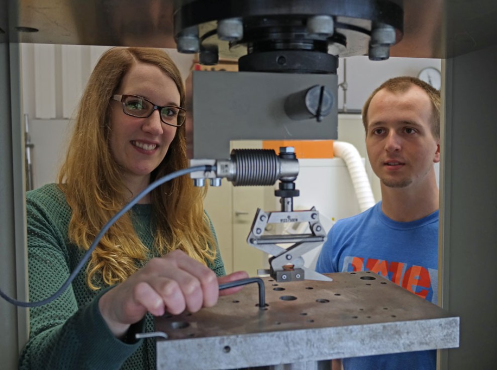 Eine Studierende und ein Studierender arbeiten an einer Maschine